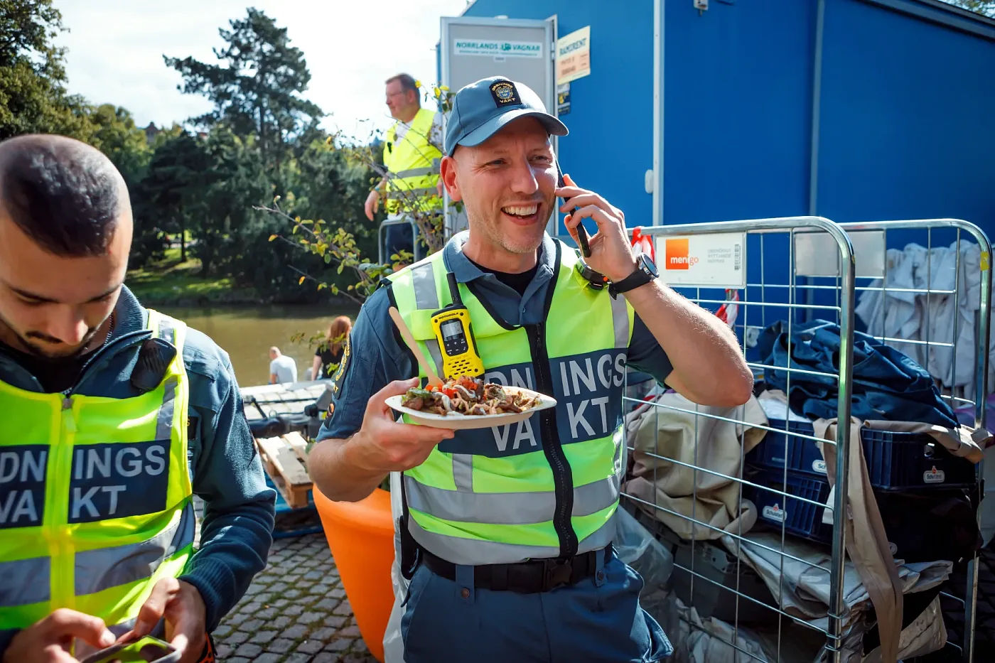 Två ordningsvakter i varselväst på festivalområdet, en av dem pratar i telefon