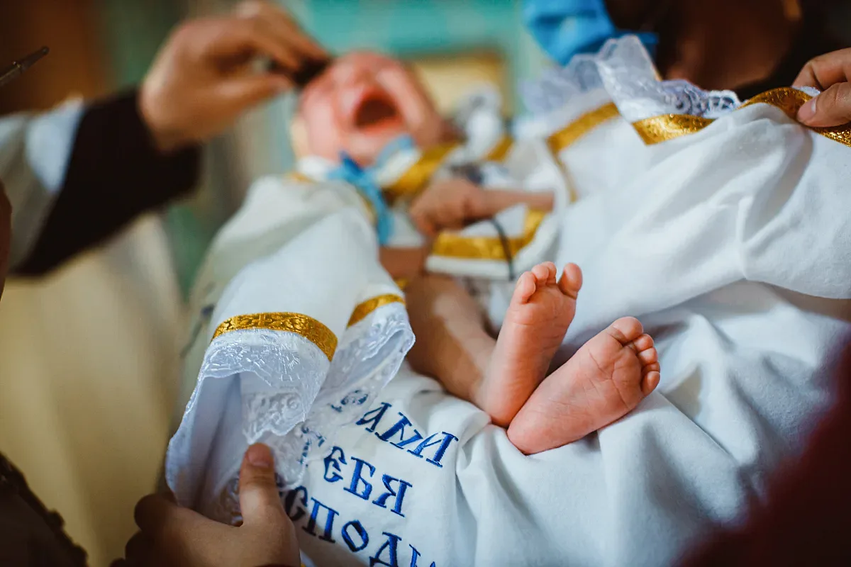 Babyns fötter i dopskjorta på en handduk