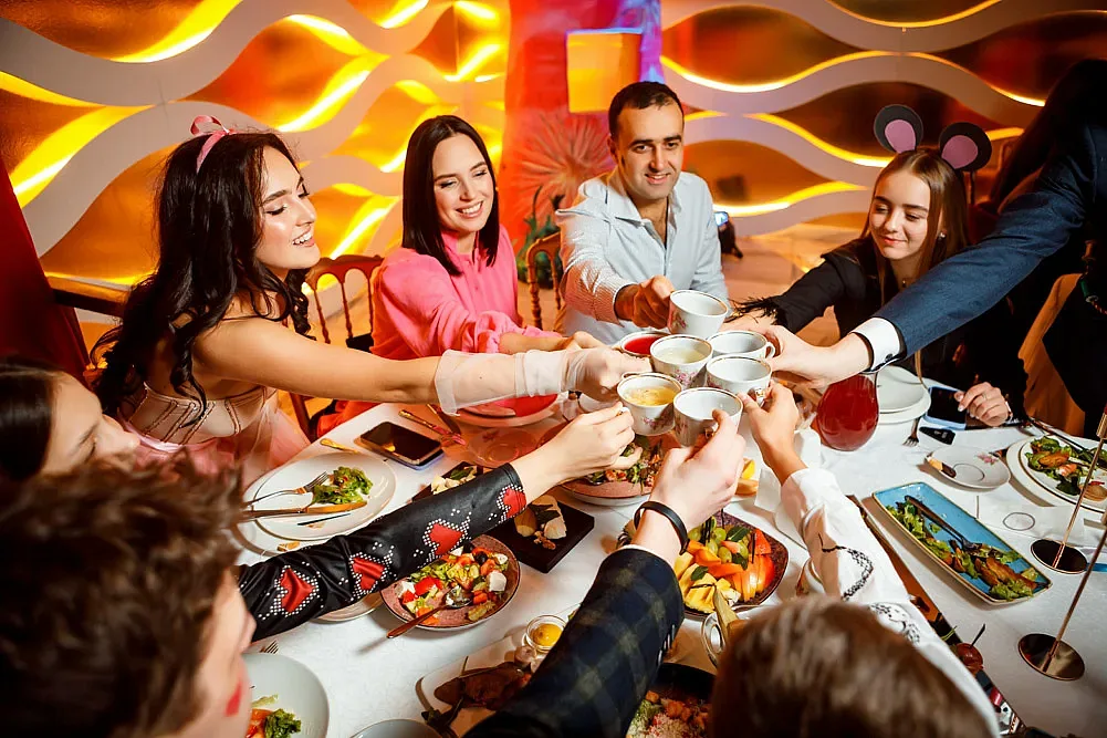 Guests raising their glasses and laughing around the laid table
