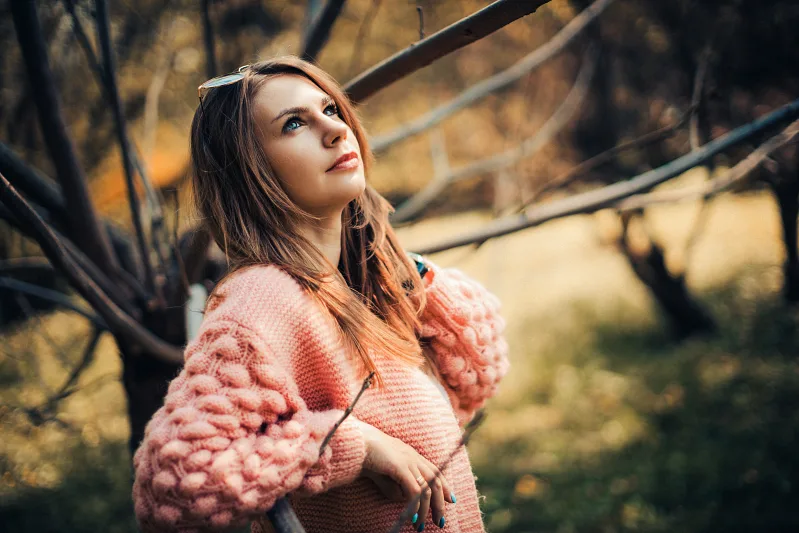 Woman in a pink knitted sweater in an autumn garden