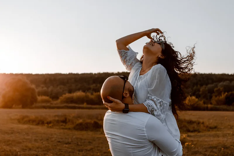 Groom lifting the bride in a field at sunset