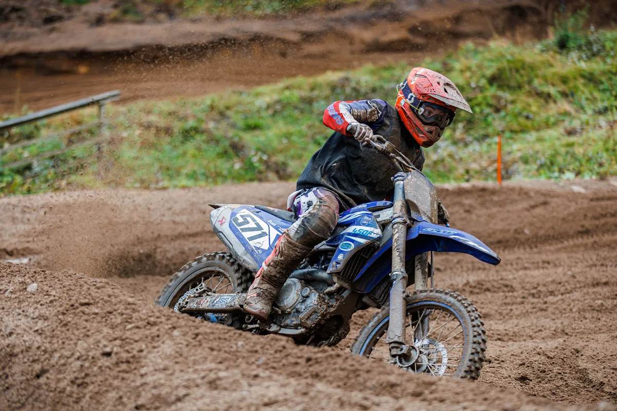 Motocross rider in an orange helmet leaning into a sandy corner, Kinds