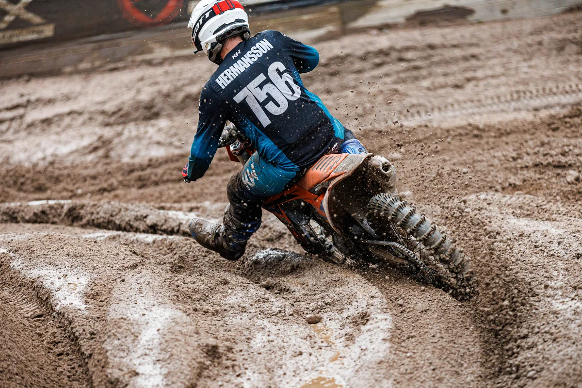 Motocross rider seen from behind throwing mud in a wet corner, Kinds
