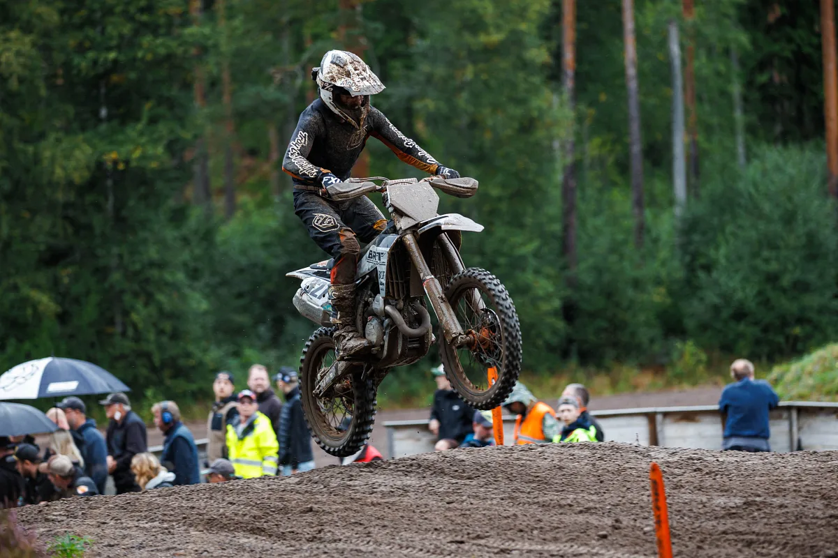 Motocross rider jumping in front of spectators with umbrellas, Kinds