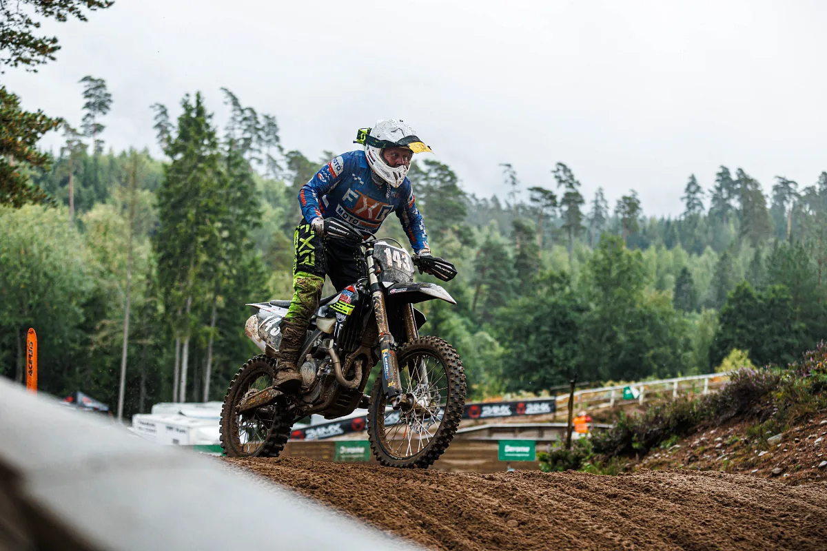 Motocross rider in blue on the edge of a track among pine trees, Kinds
