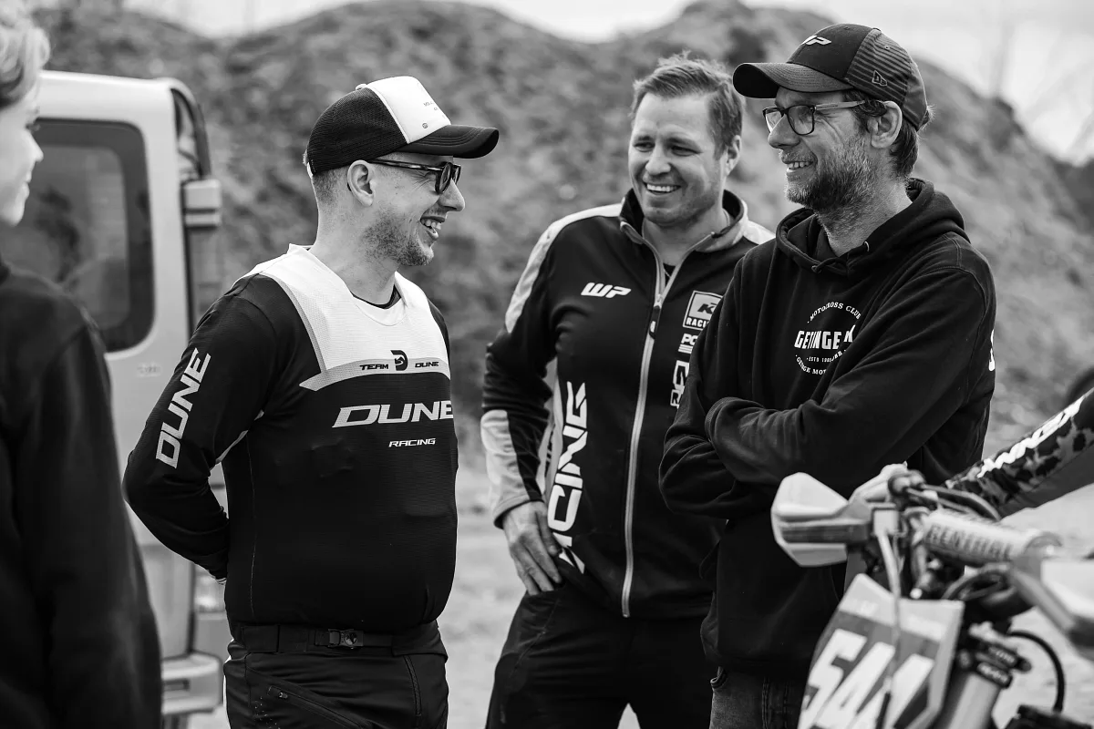 Three team members laughing in the pit area, black and white, Alingsås