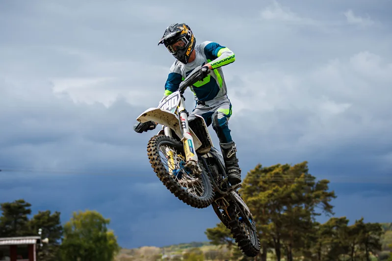 Motocross rider in the air on a white bike against a stormy sky, Varberg