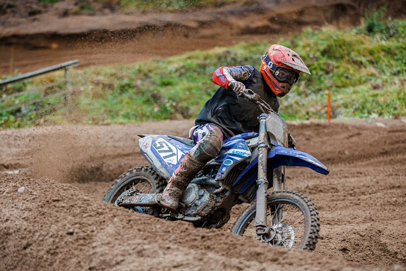 Motocross rider in an orange helmet leaning into a sandy corner, Kinds